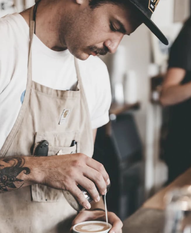 an attendant in a coffee shop preparing a coffee